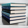 Black and blue hardcover real books staged and used as home décor. Book stack on a shelf.