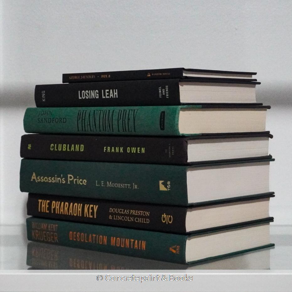 Black and green hardcover real books staged and used as home décor. Book stack on a shelf.