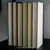 Black and blue hardcover real books staged and used as home décor. Book stack on a shelf.