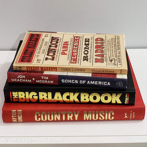 Stack of real books staged for display. Coffee tables books in red black and brown. 