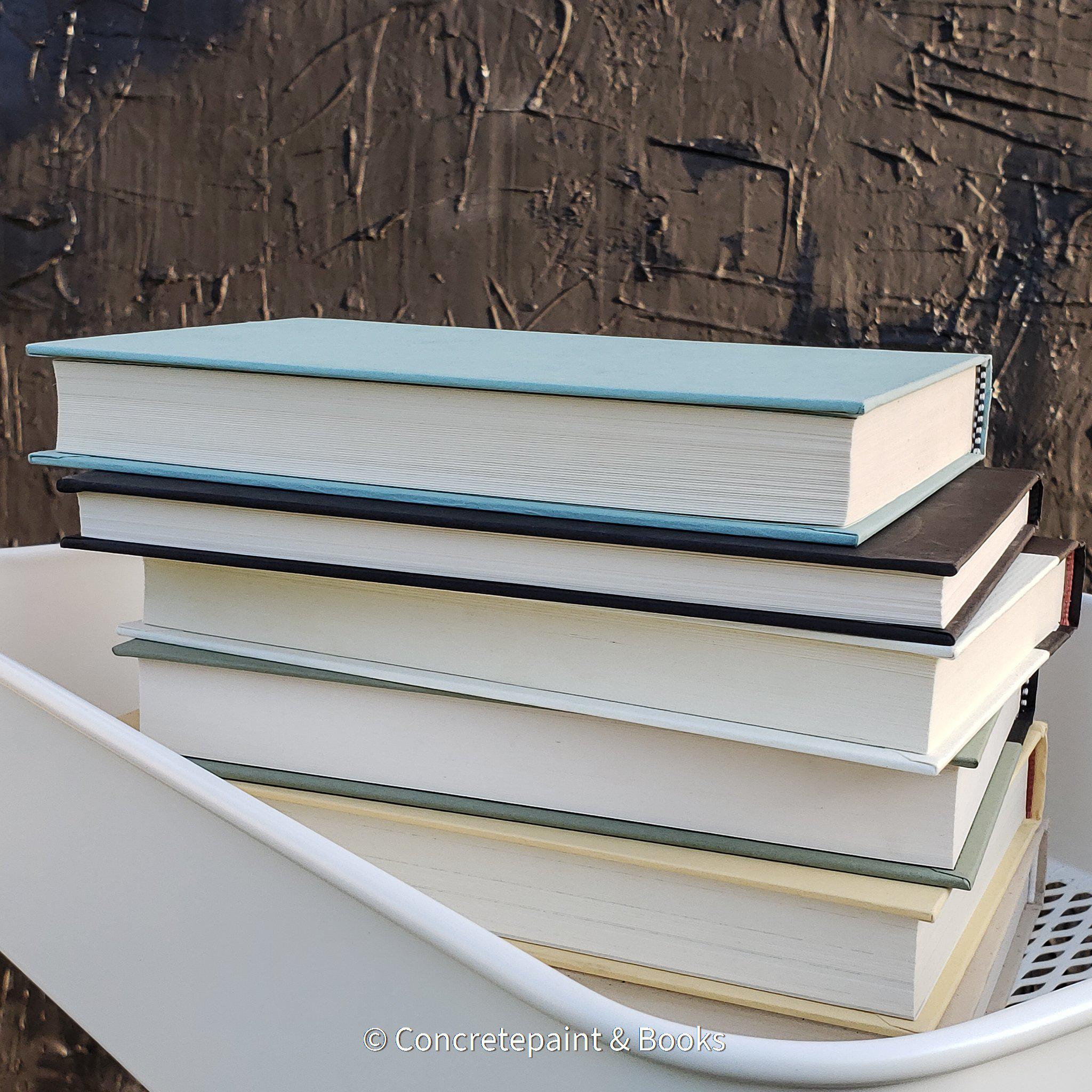 large stack of hardcover books staged and used for decorating display. Teal, neutral, black , and mint green décor. 