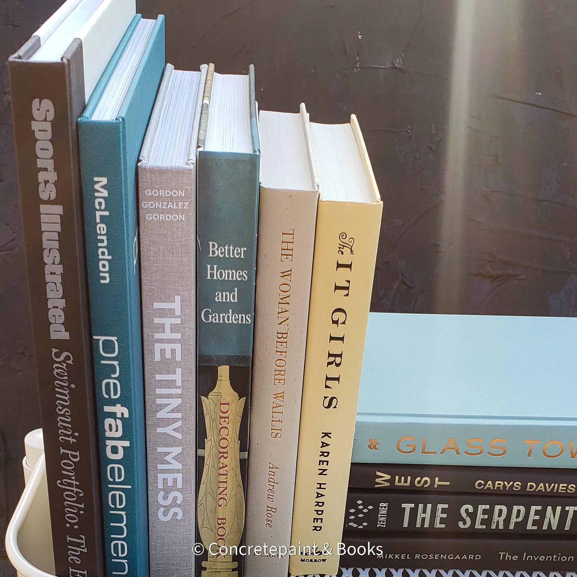 large stack of hardcover books staged and used for decorating display. Teal, neutral, black , and mint green décor. 