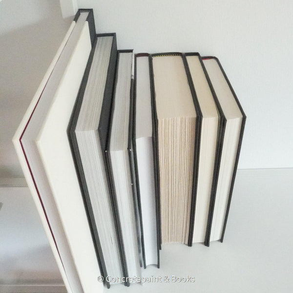 Real books used as home décor. Stack of all black hardcover books including coffee table books, and novels.