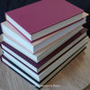 Stack of burgundy, blush, and neutral color books. Real hardcover books used for decorating.