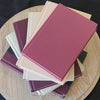 Stack of burgundy, blush, and neutral color books. Real hardcover books used for decorating.