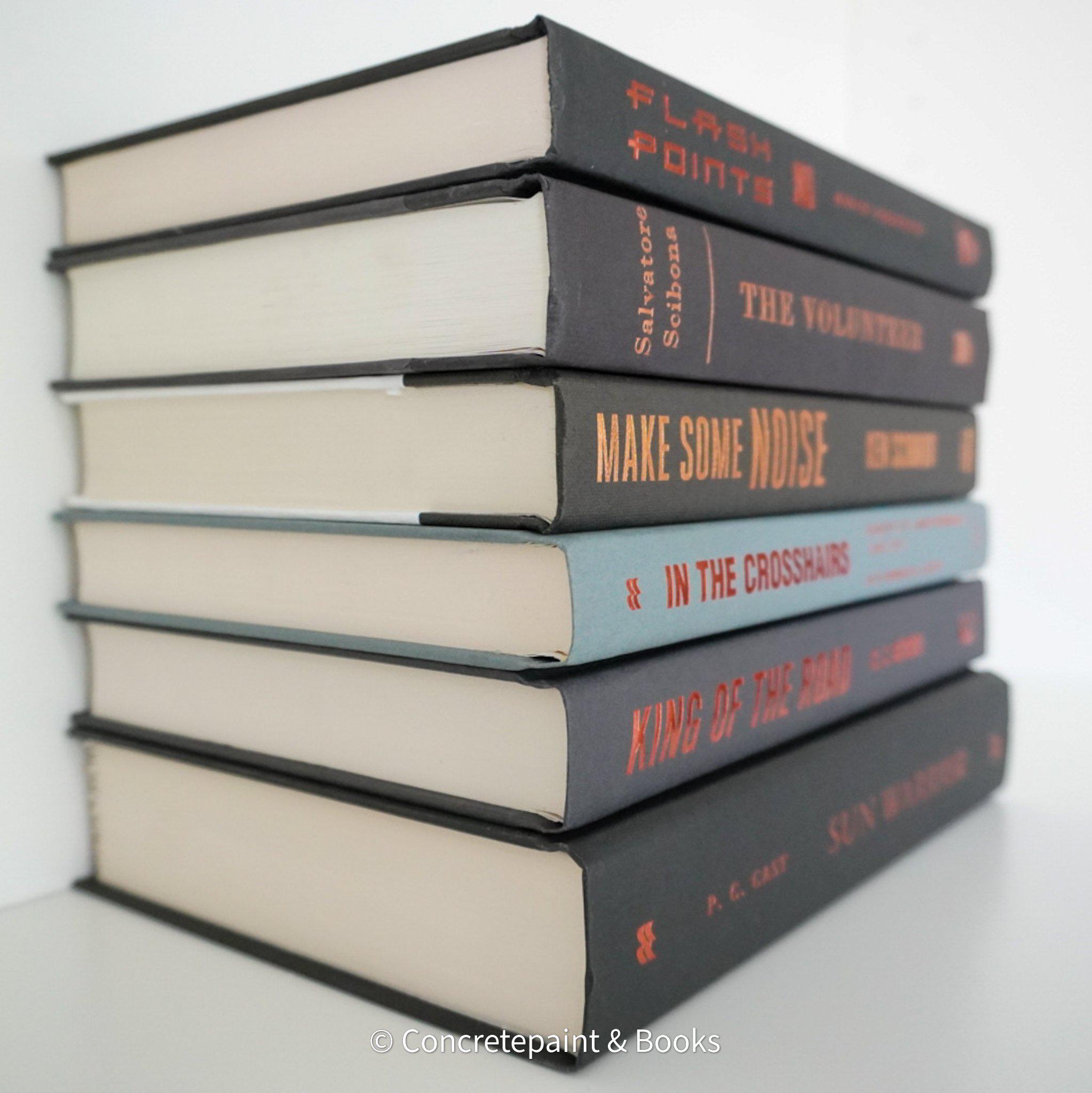 Stack of black and gray hardcover books with copper font. Real books staged and used as shelf décor.