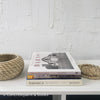 Real headcover books used as staged home décor. Stack of large black oblong coffee table books with ikea seagrass basket.