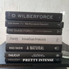 Stack of hardcover books in purplish gray and black.