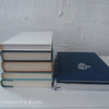 Real hardcover books staged as home décor. Blue, white, green and brown hardcover books.