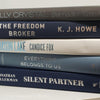 stack of real hardcover books used as shelf décor in blues, white, and gray.