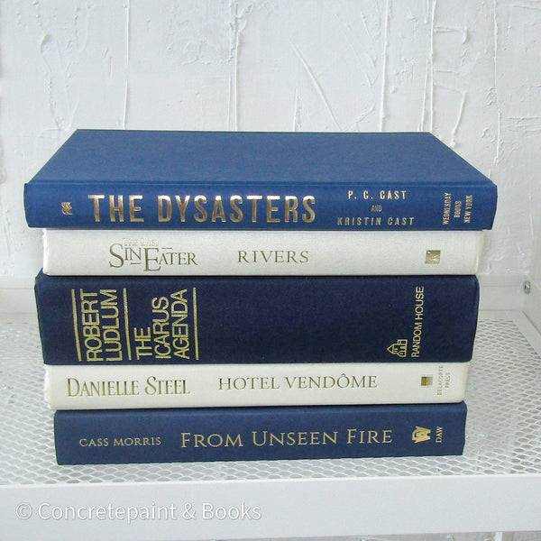 stack of real hardcover books in navy blue and neutral colors. 