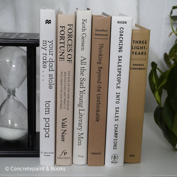 Neutral, sand and white books on display. Real hardcover books for decorating shelves.