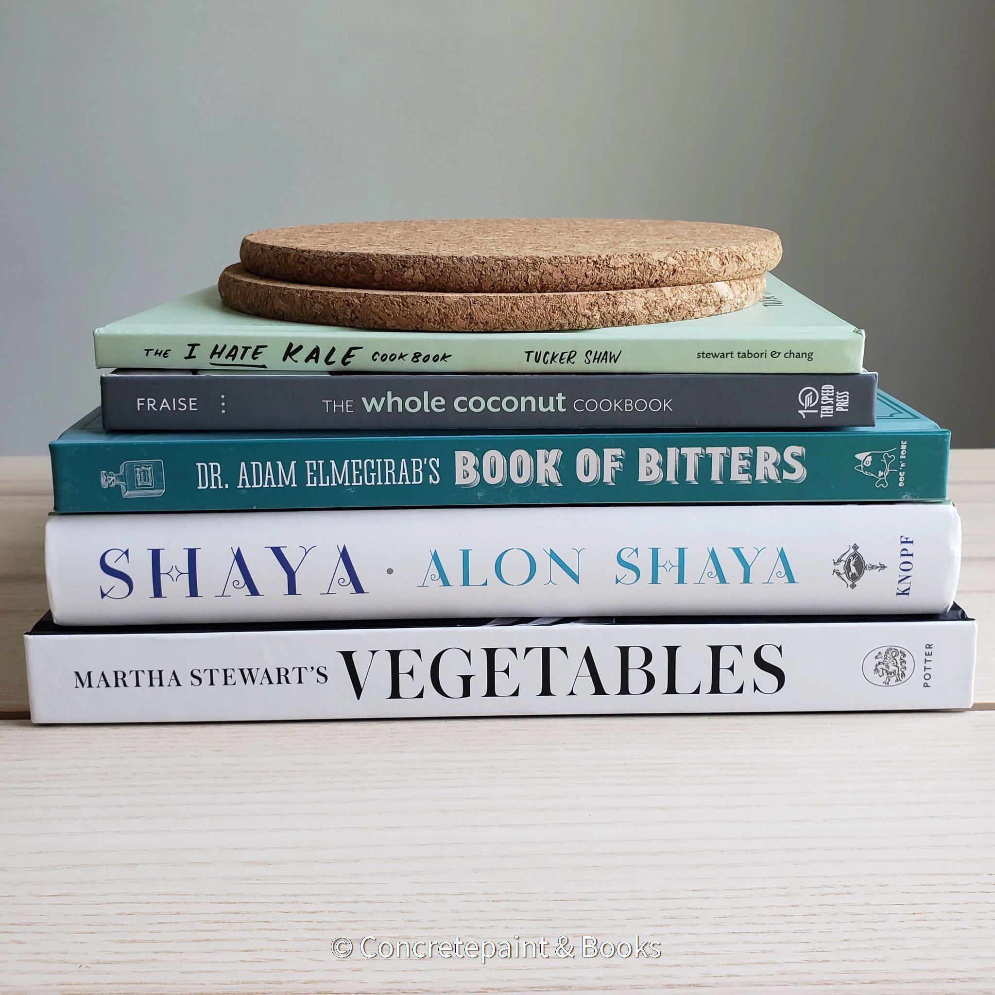 stack of blue white gray and green cookbooks for display with ikea cork heat trivets 