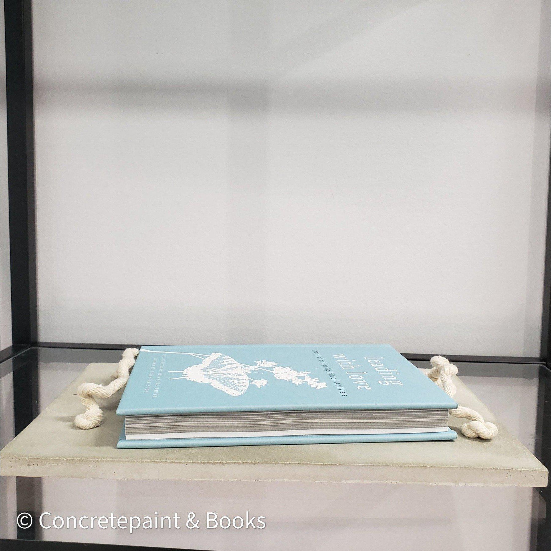 Decorative concrete tray with light blue hardcover book on top. Leading with Love Book and concrete home décor.