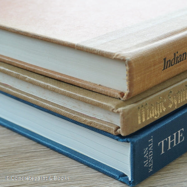 Stack of blue and brown hardcover books used as men's coffee-table décor. 