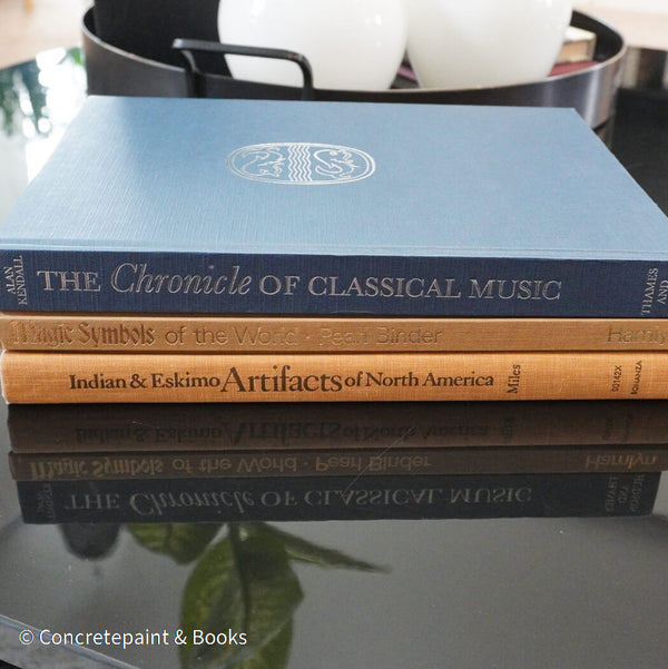 Stack of blue and brown hardcover books used as men's coffee-table décor. 