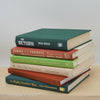 Real books as display on shelf. Hardcover green, neutral, and terra cotta color.