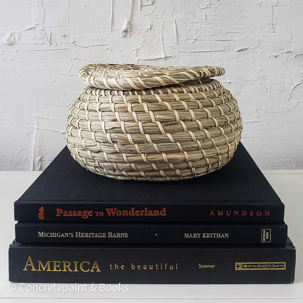 Real headcover books used as staged home décor. Stack of large black coffee table books with ikea seagrass basket on top. Mens bachelor pad decor for sale.